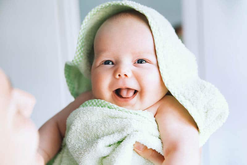 cute little baby smiling wearing towel after bath