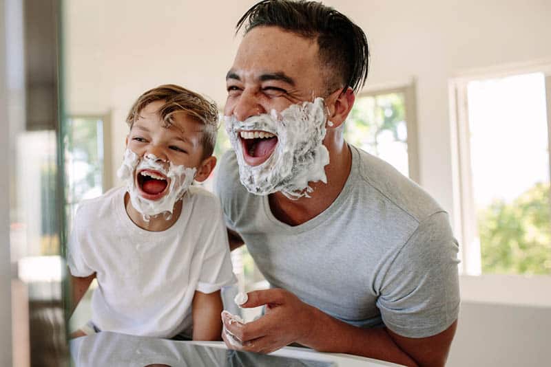 cute little kid playing with father in bathroom with shaving cream
