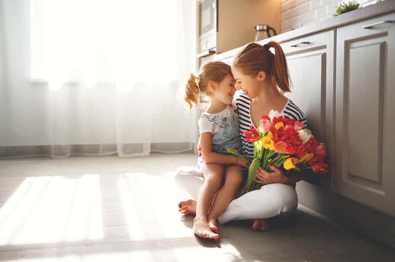  daughter congratulates mother and gives a bouquet of flowers on the floor