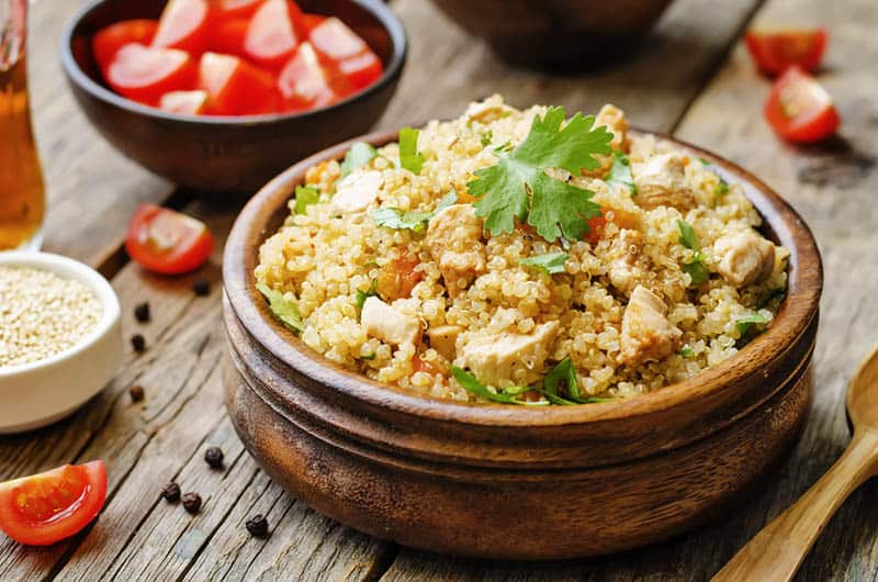 delicious meal made from quinoa and chicken in wooden bowl on the table