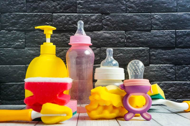 detergent for baby bottles with baby dishes and a sponge on the table