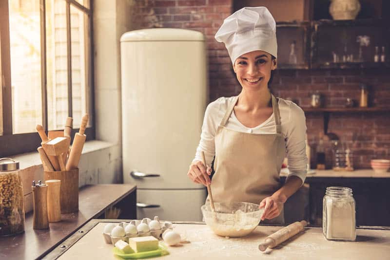 happy woman baking a cake in the kitchen with coolinary hat on the head