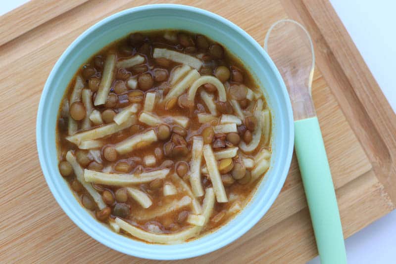 lentil noodles in a baby bowl with spoon on the wooden board