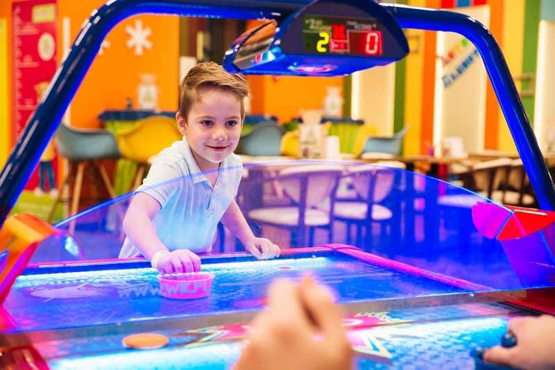 little boy playing air hockey at an arcade