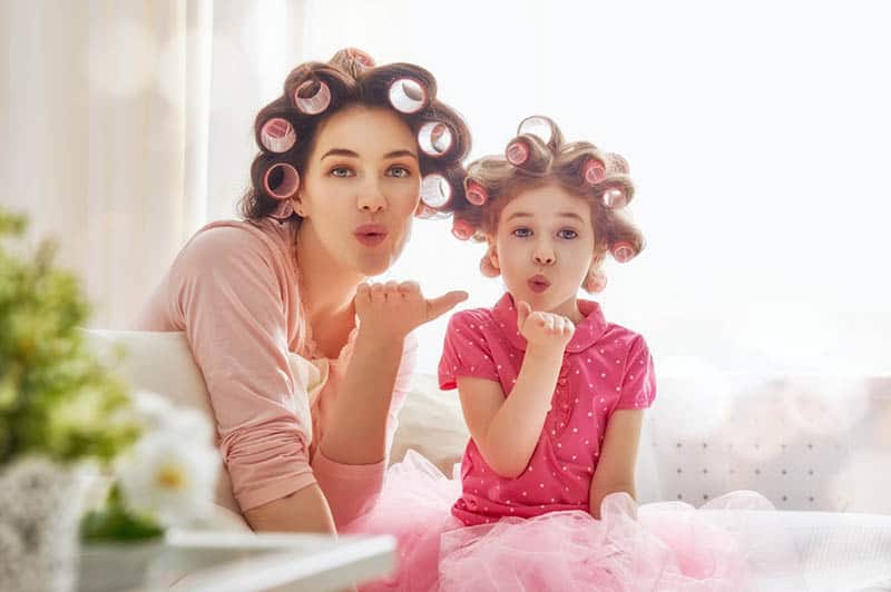 mother and daughter doing their hair in bedroom and sending kisses