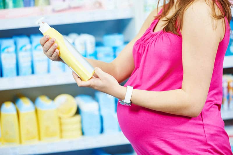pregnant woman holding a shampoo in a cosmetic store