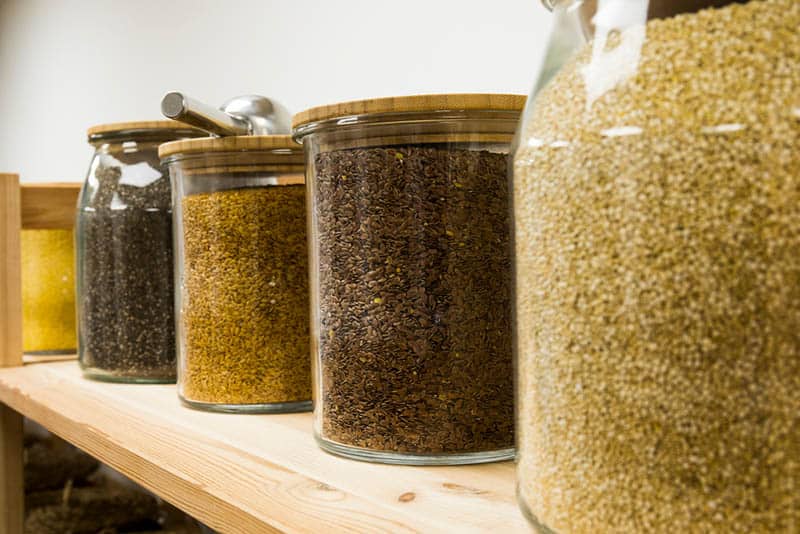 quinoa grains in big glass jars on the wooden table in store