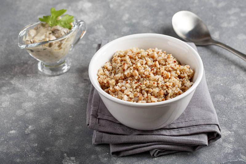 quinoa porridge in white bowl with spoon on the kitchen cloth 