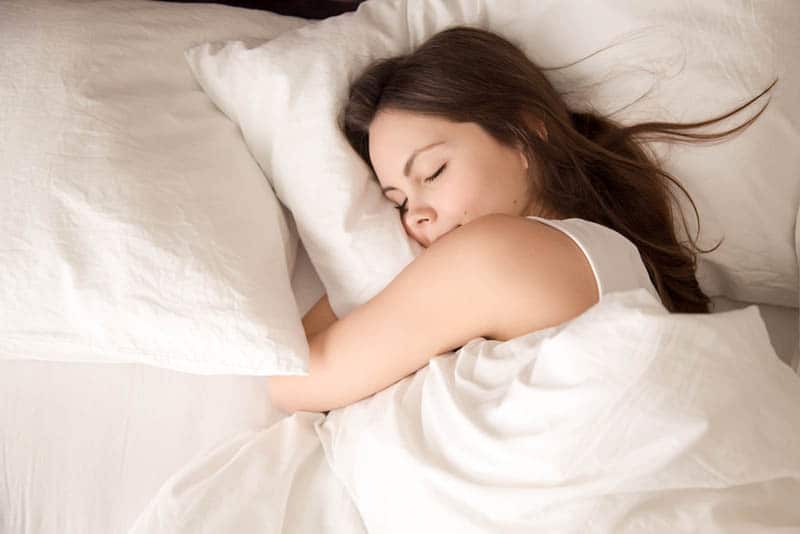 relaxed young woman sleeping on belly in the bed