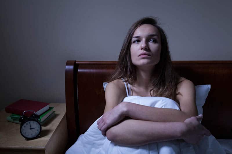 serious woman sitting in bed in deep thoughts