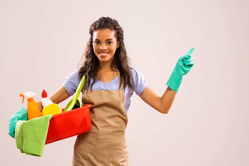 smiling young woman holding in hands cleaning products ready to clean