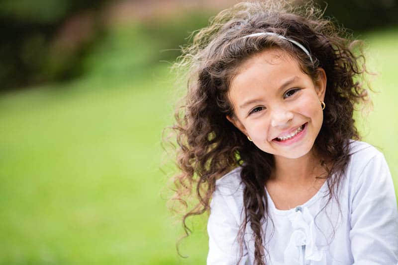 sweet little girl with curly hair smiling and posing outdoor