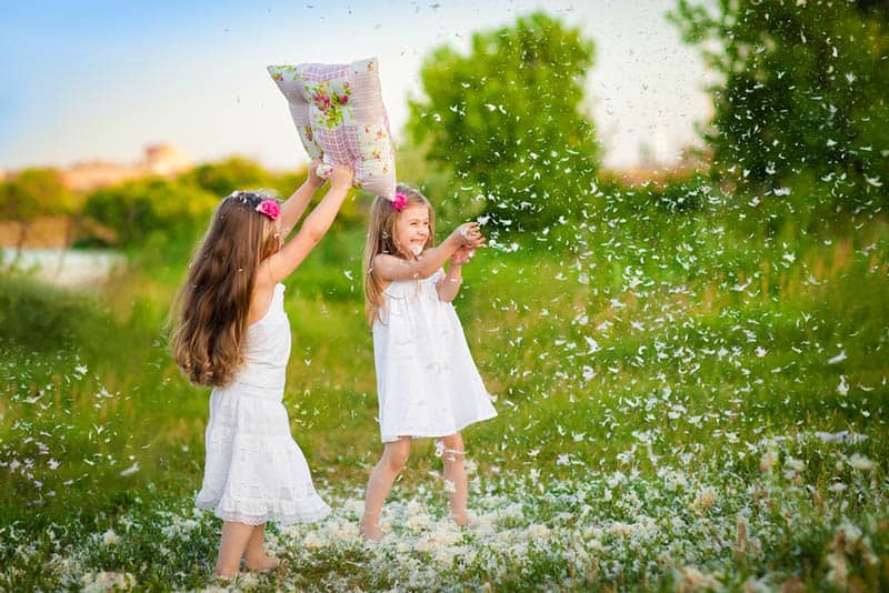 two girls playing with pillow plumage outdoor