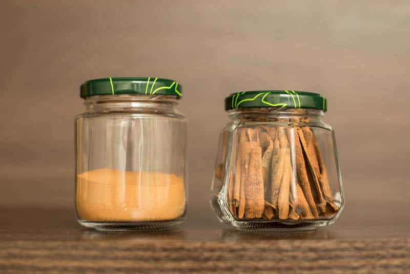 two jars of cinnamon in different types on the wooden table