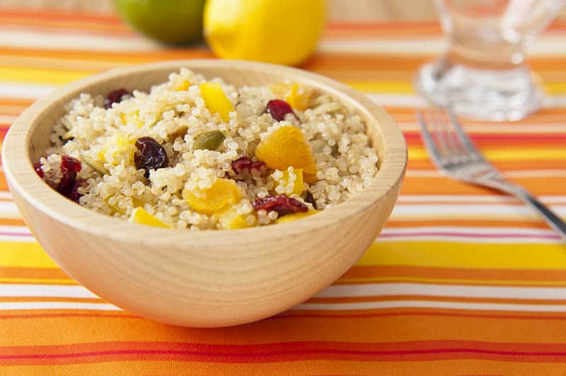 wooden bowl full of quinoa seeds and fruit on the colorful table