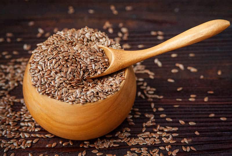 wooden bowl of flax seeds with spoon on the table