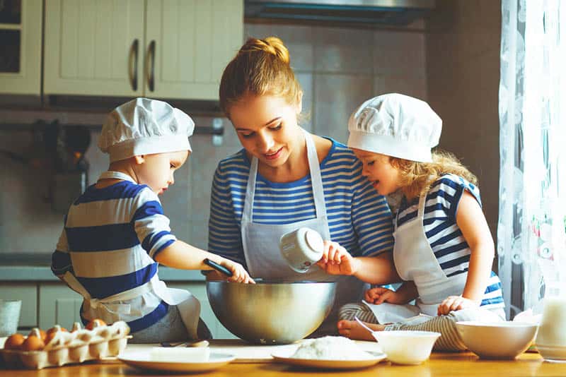 young mother cooking together with her kids in the kitchen