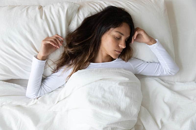 young woman sleeping in comfortable bed and dreaming