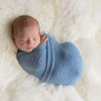 newborn baby sleeping in a blue swaddle