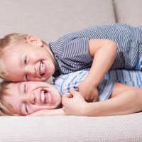 smiling little brothers playing on the couch