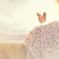 a butterfly lands on the shoulder of a girl