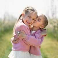 happy twin sisters hugging outside