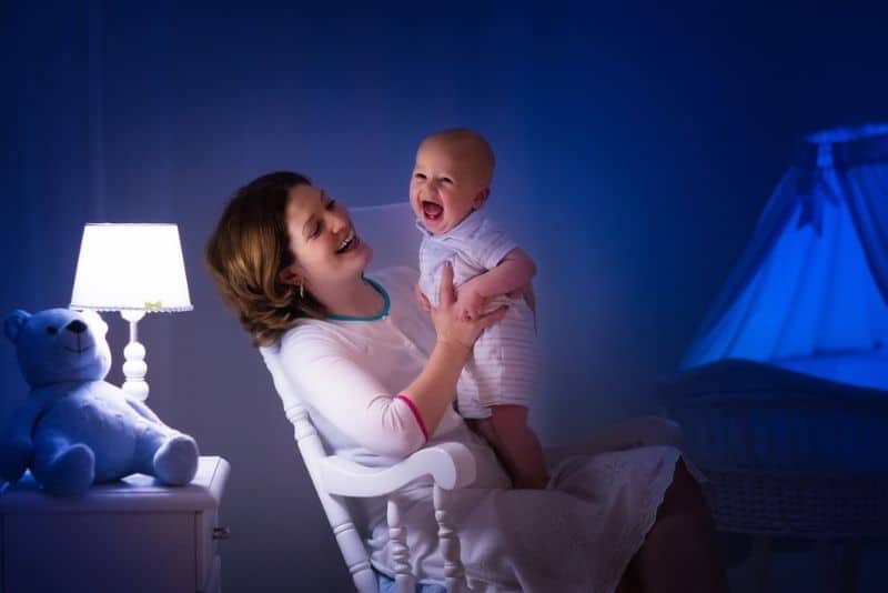 Mother holding smiling baby late at night
