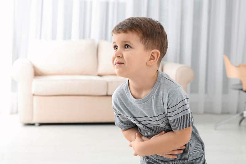 Little boy suffering from nausea in living room