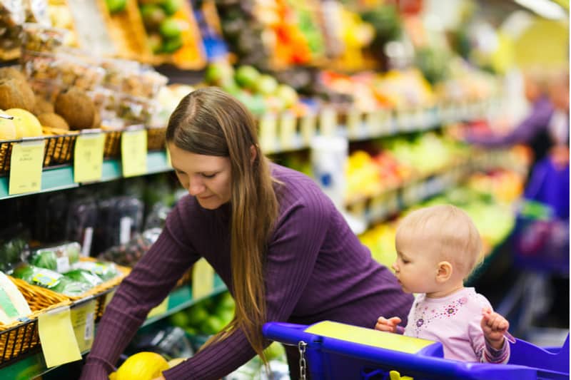 Mother and baby daughter in supermarket buying fruits and vegetables