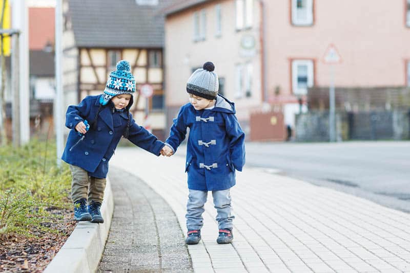 Two little sibling boys walking on the street in winter