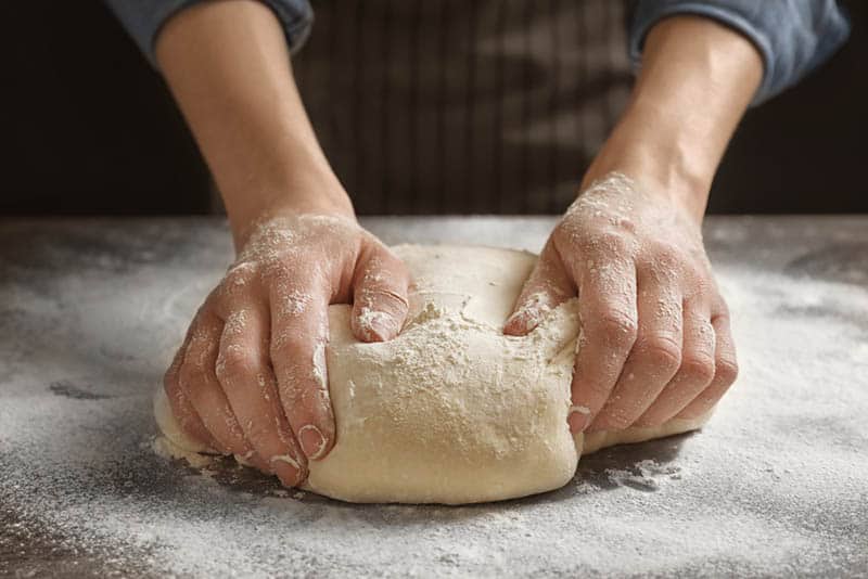 Woman kneading dough on the wooden table