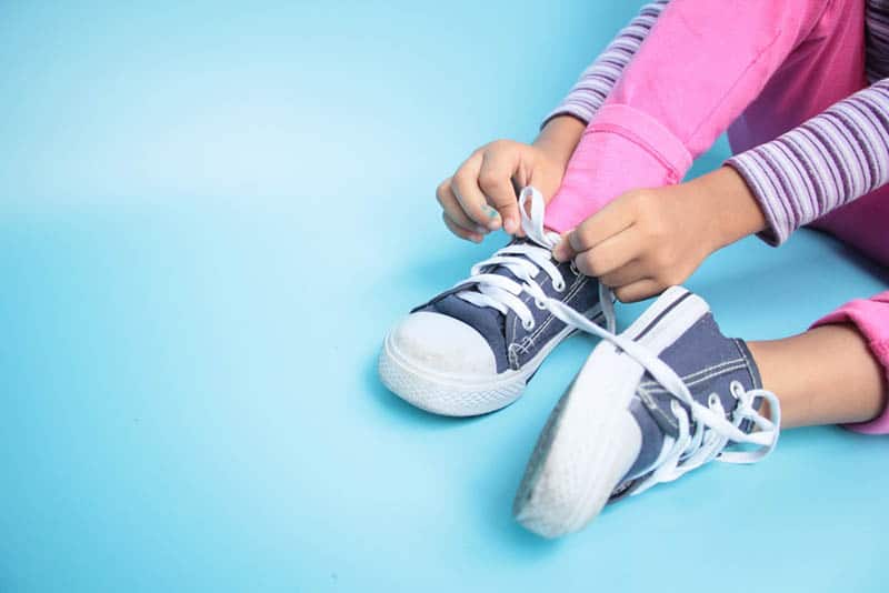 Young girl learning to tie her shoes