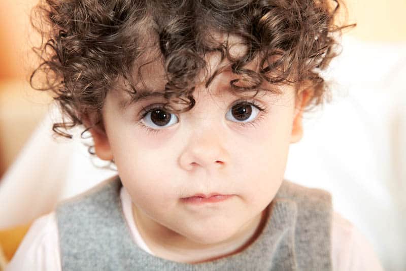 adorable baby boy with curly hair posing