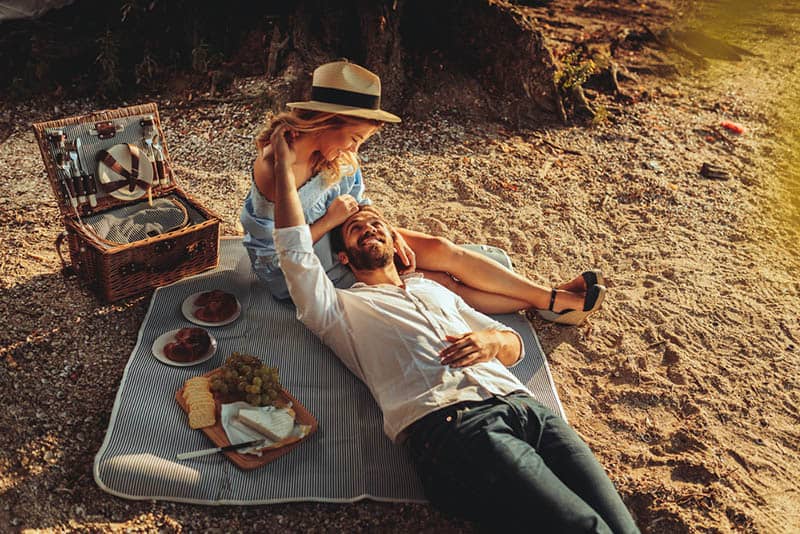 beautiful young couple cuddling on picnic in nature