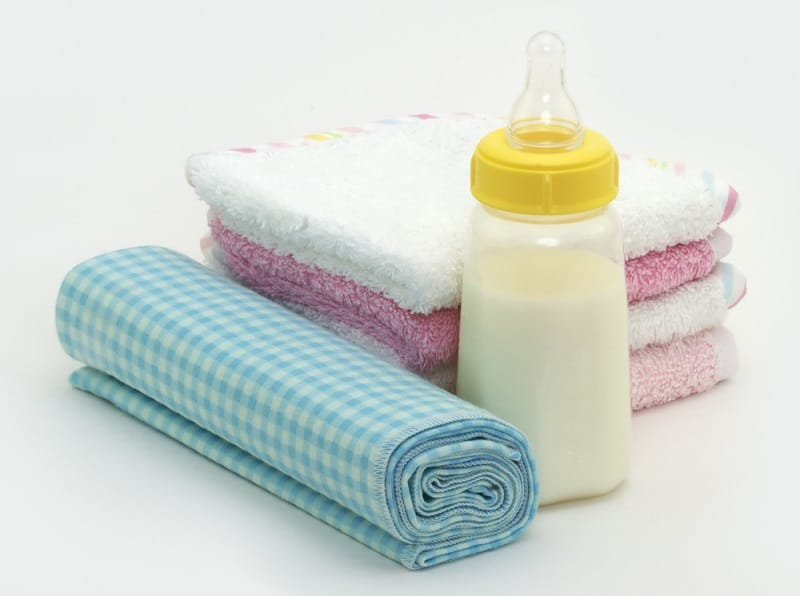 colorful burp cloths and a baby bottle placed on a white table