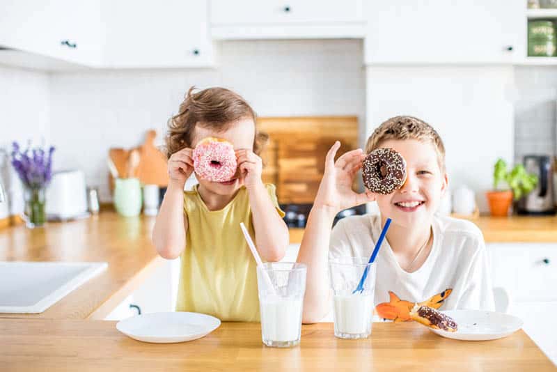children having fun with donuts for breakfast at home