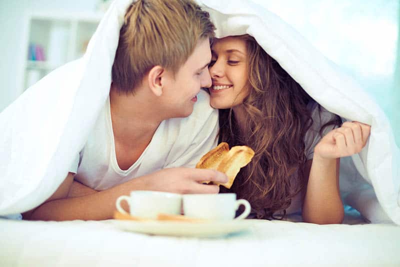 couple cuddling in the bed with morning breakfast
