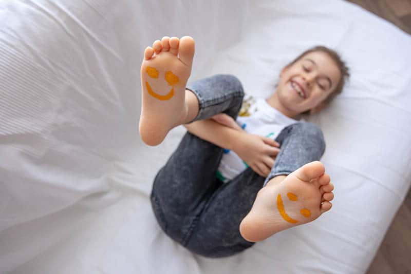 cute little girl smiling with smiley on her barefoot legs