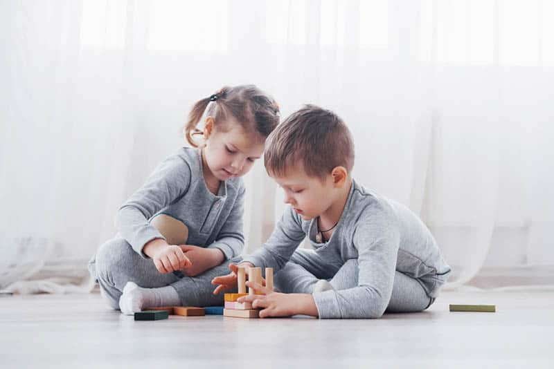 cute sister and brothet playing with toys on the floor