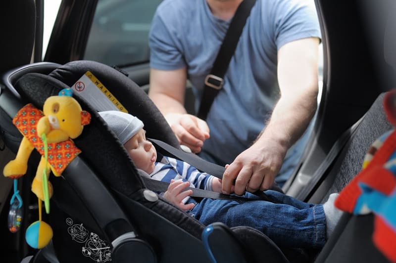 dad putting his baby into the infant car seat