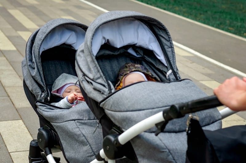 mother pushing twins in a double stroller