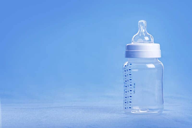 glass baby bottle on the blue table