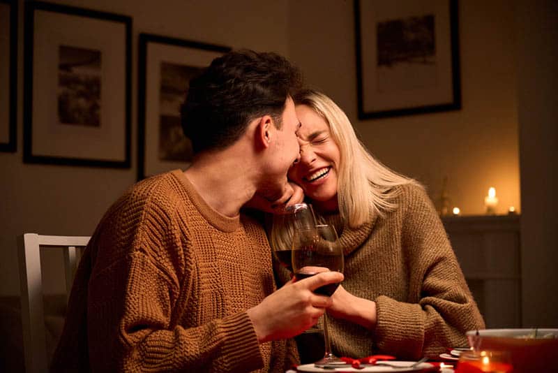 happy couple drinking wine on celebration at home with candles