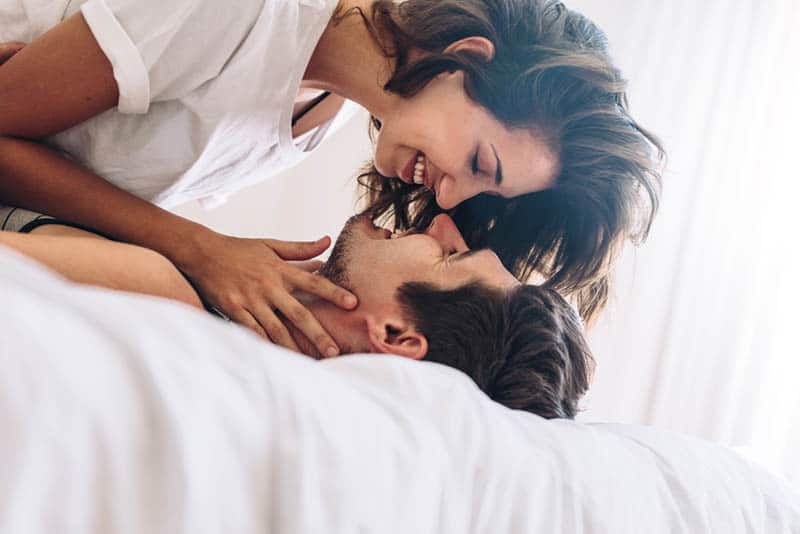 happy woman kissing man on the bed in morning