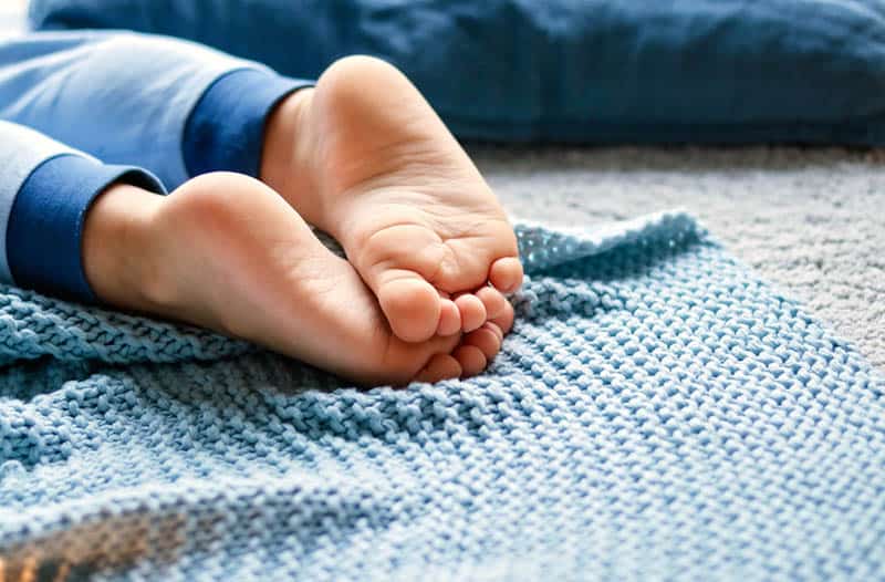 little boy lying on the bed with barefoot legs