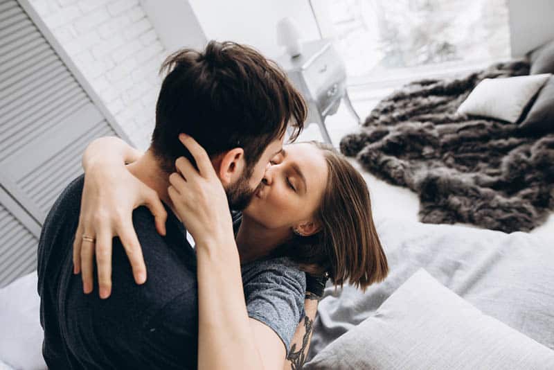loving couple kissing on the bed while in hug