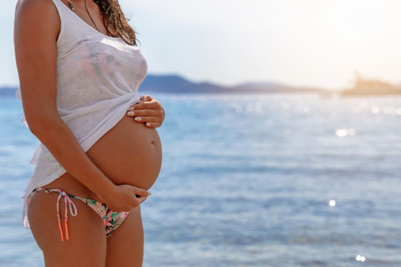 pregnant woman in bikini standing on the beach