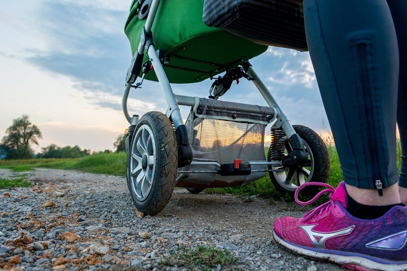 stroller wheels next to a woman's running shoes