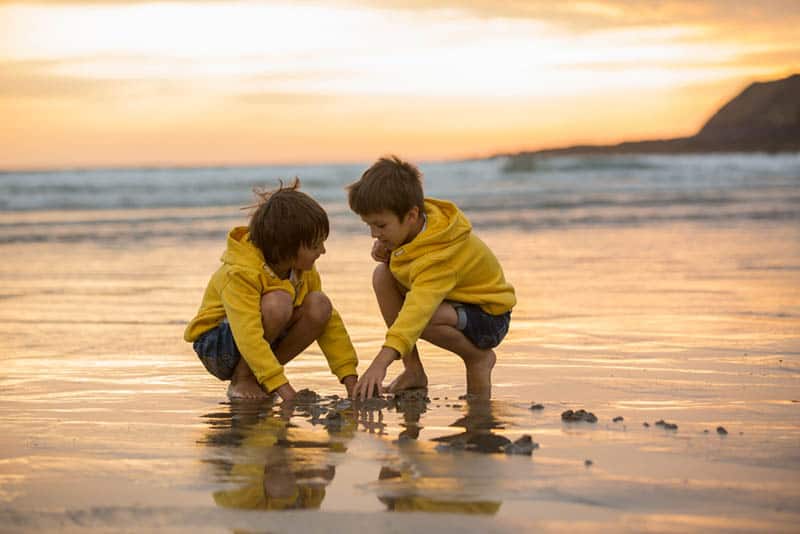 two boys playing in the sand on the beach