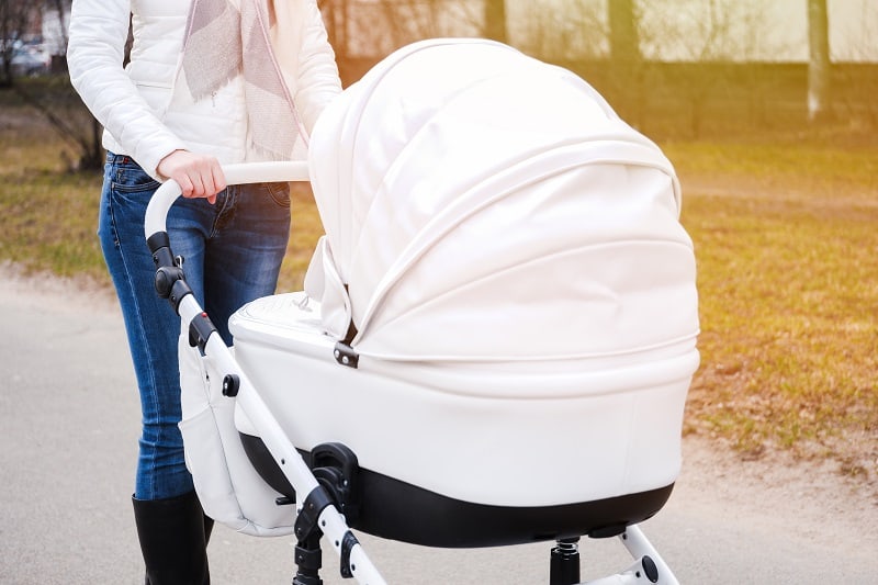 mother pushing a white baby stroller with canopy
